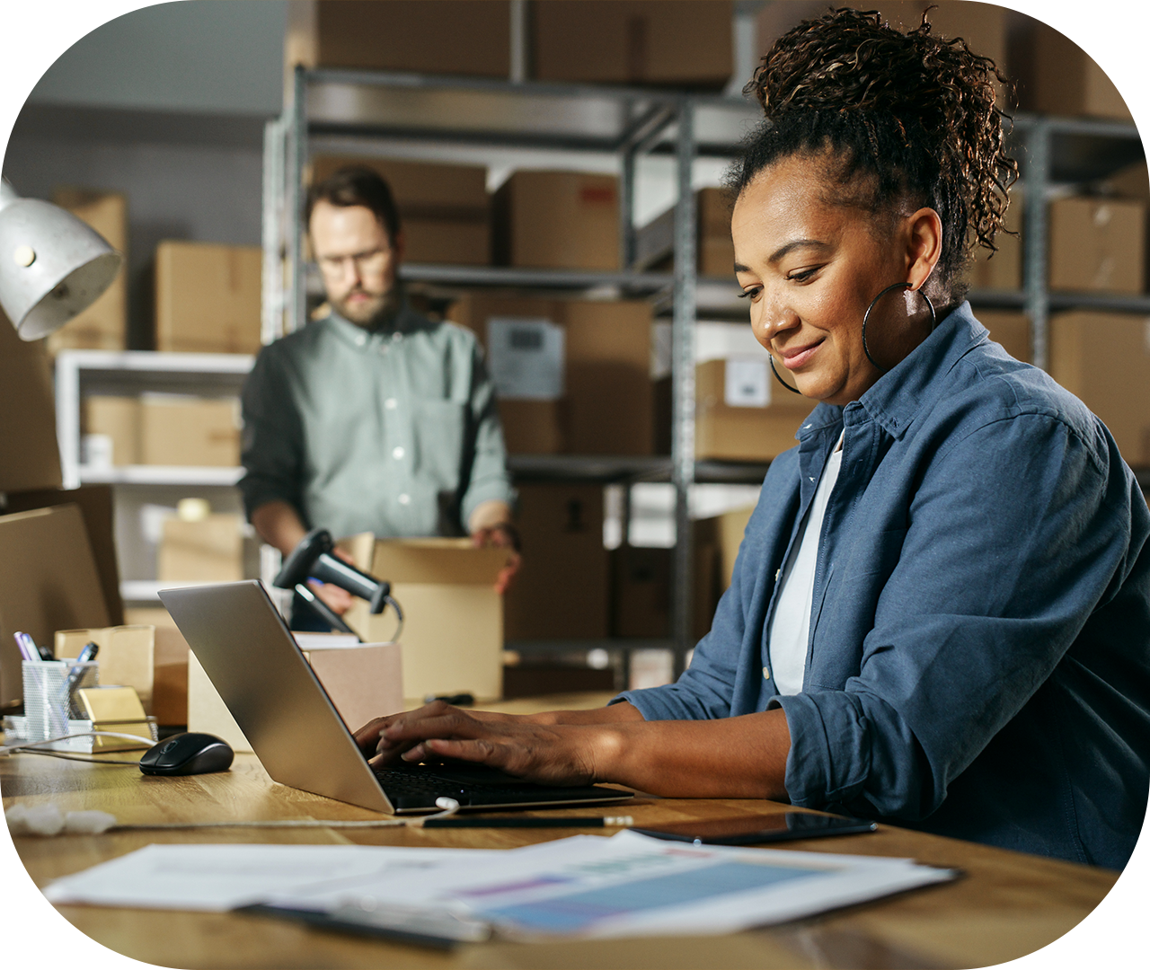 Diverse-Male-and-Female-Warehouse-Inventory-Managers-Talking,-Using-Laptop-Computer-and-Checking-Retail-Stock.-Rows-of-Shelves-Full-of-Cardboard-Box-Packages-in-the-Background-1478421401_1280x1080-1